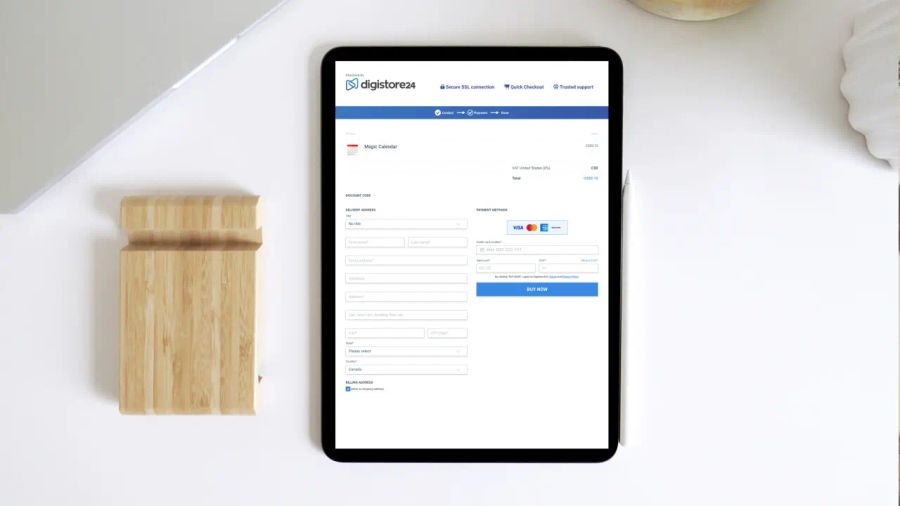 A tablet displaying a Digistore24 online checkout page on a white desk next to a wooden phone stand.
