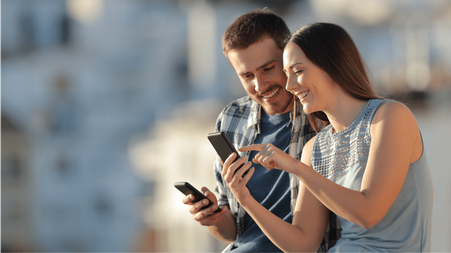 A smiling man and woman looking at a smartphone together.