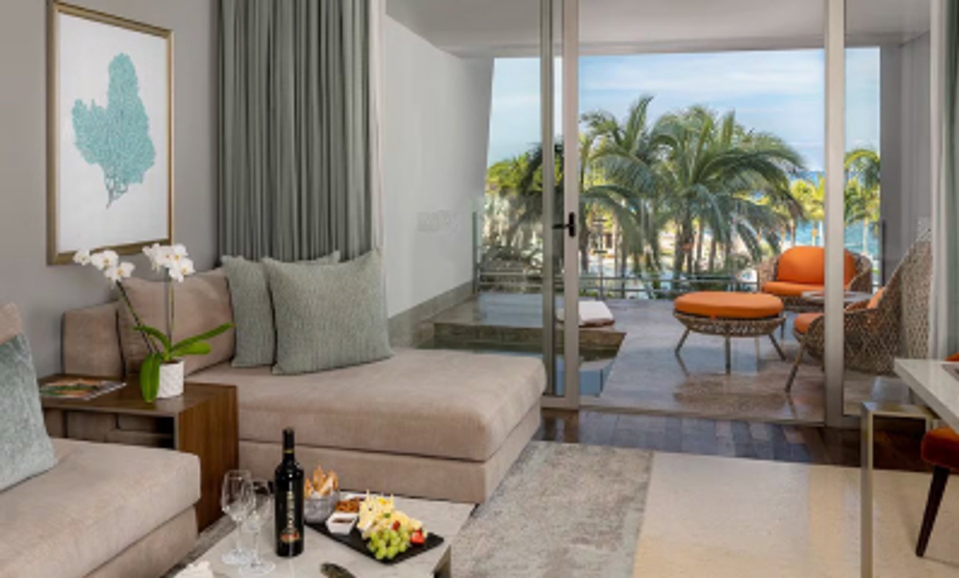 Modern living room with a balcony view of palm trees, outdoor seating, and the ocean.