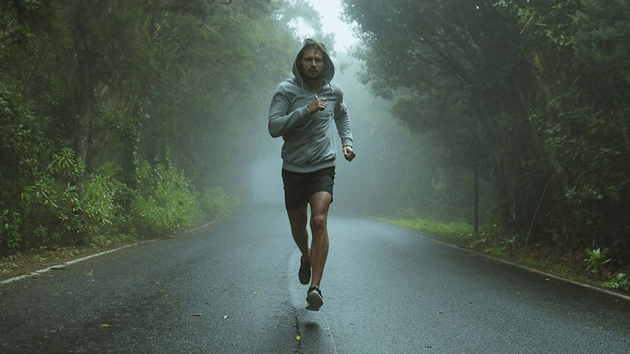A man runs on a misty forest road.