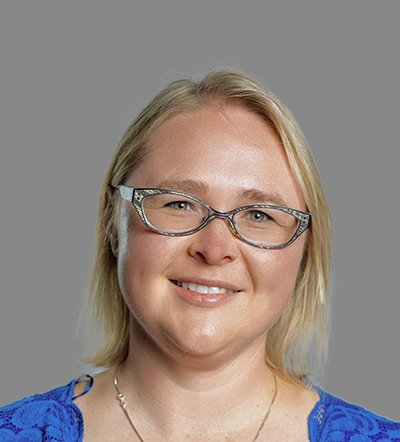 Smiling blonde woman in glasses and a blue top.