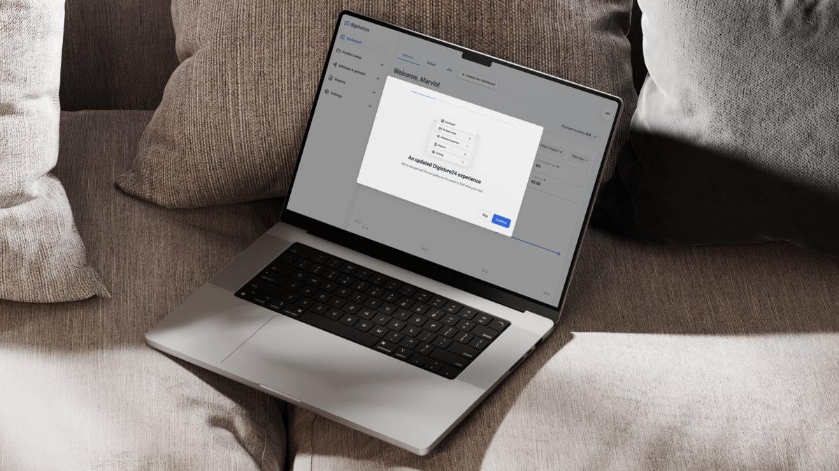 A silver laptop rests on a beige sofa, displaying a web application with a dialog box open on the screen.