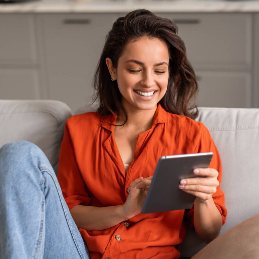 Smiling woman on couch using a tablet.
