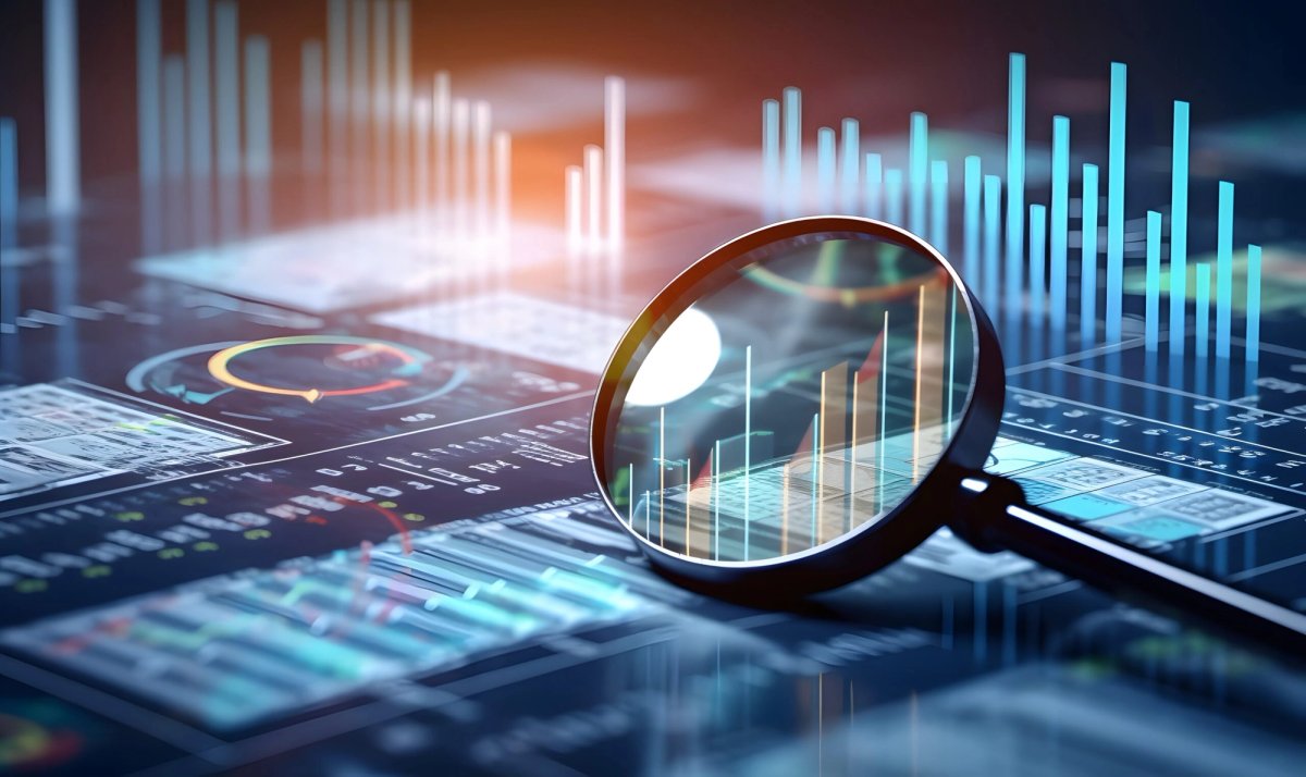 Magnifying glass over a digital screen displaying charts and graphs.
