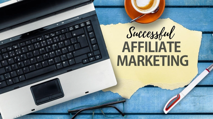A laptop, coffee cup, and glasses on a blue wooden surface next to a paper note that reads "Successful AFFILIATE MARKETING."