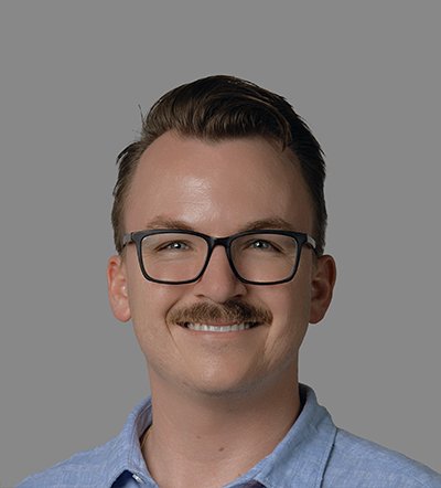 A man with glasses and a mustache smiles at the camera.