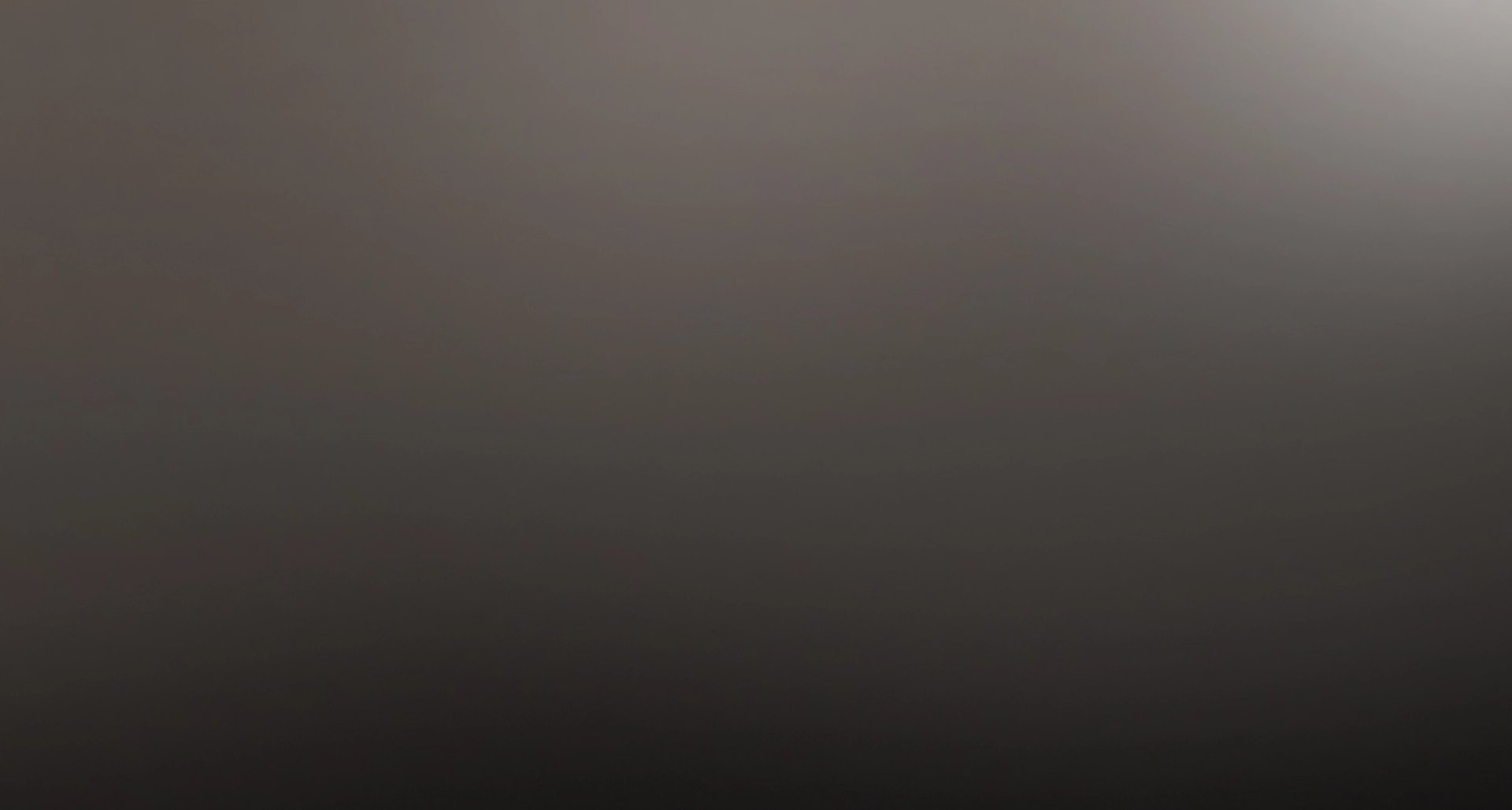 A dark gray-brown background with a subtle light gray glow in the upper right corner.