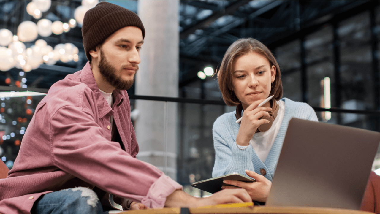 A man and a woman collaborating while looking at a laptop.