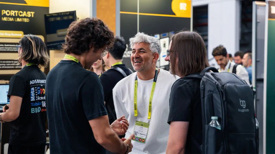 Three men laughing and talking at the Portcast Media Limited booth.