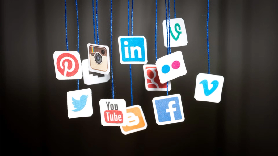Various social media logos, including Pinterest, Instagram, LinkedIn, Twitter, YouTube, and Facebook, hanging on strings.