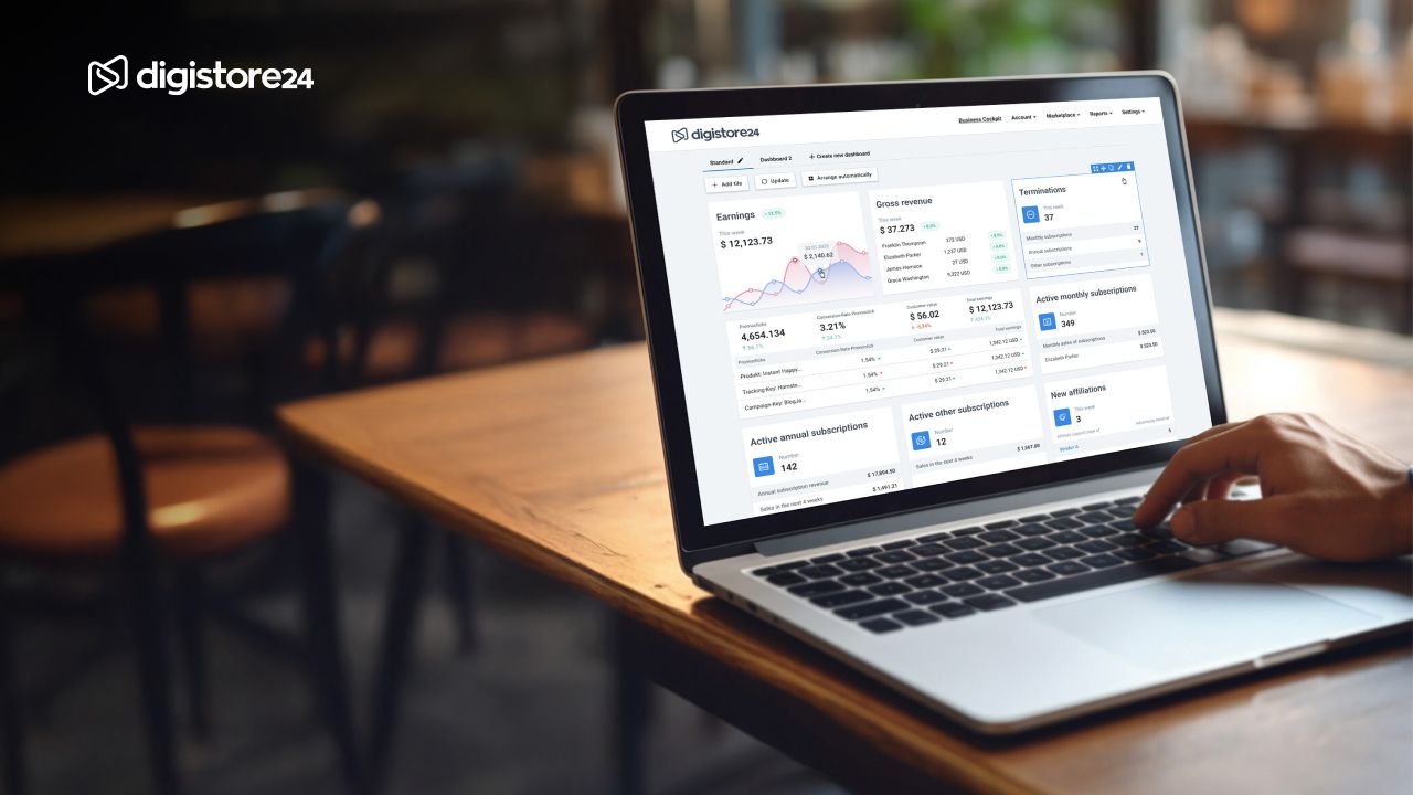 A hand types on a laptop displaying the Digistore24 business dashboard.