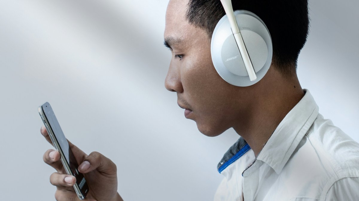 Man in white Bose headphones looking at a smartphone.