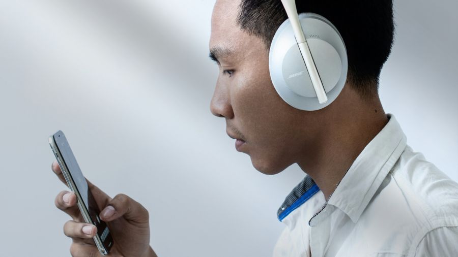 Man in white Bose headphones looking at a smartphone.