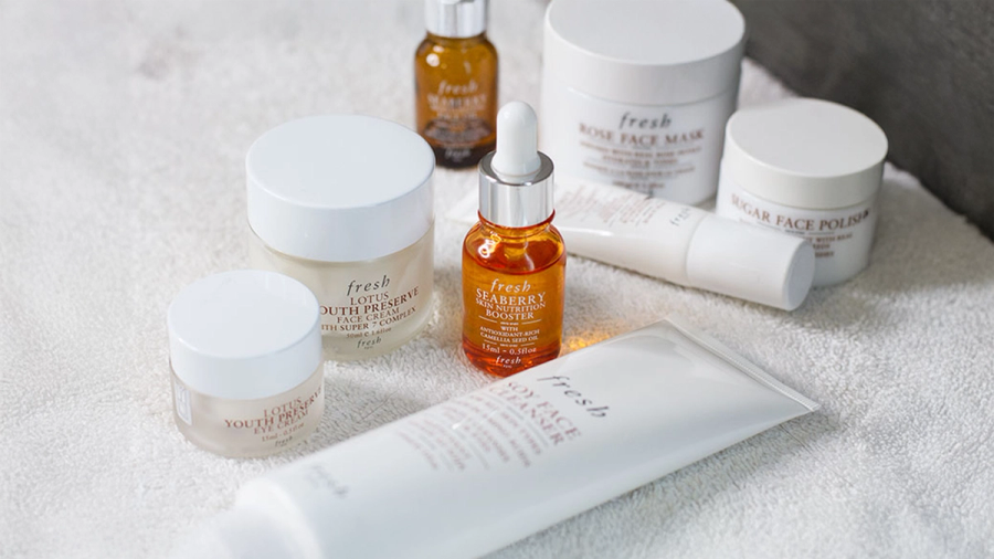 A collection of Fresh brand skincare products on a white towel.