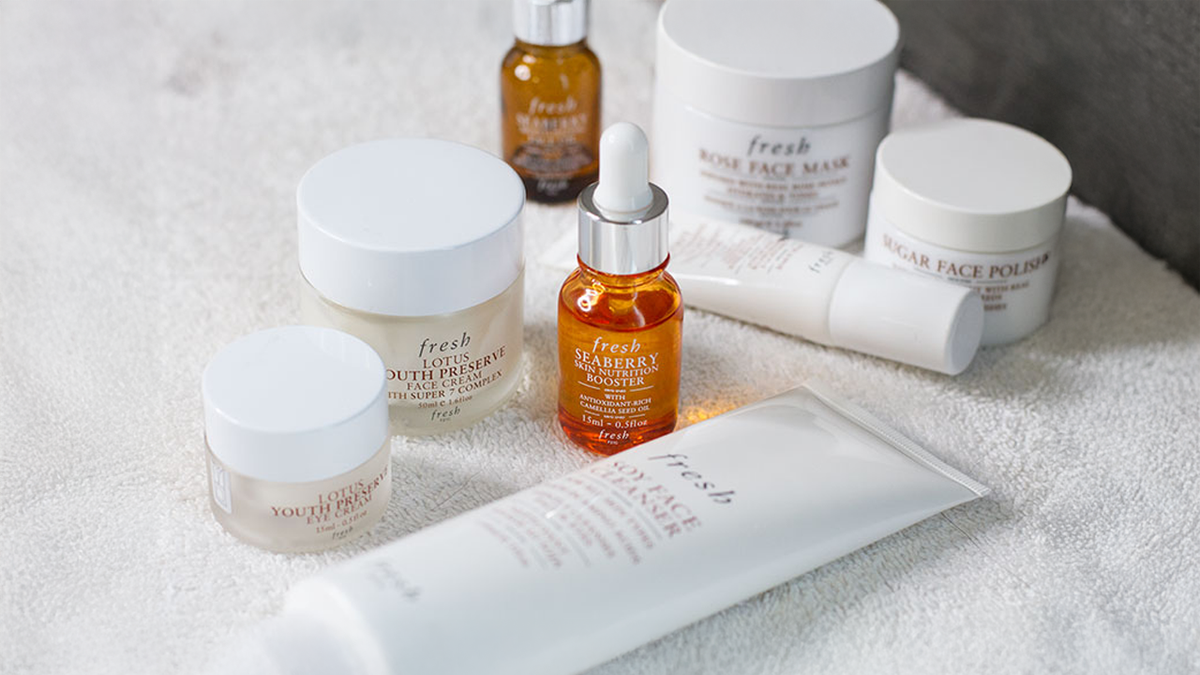 A collection of Fresh brand skincare products on a white towel.