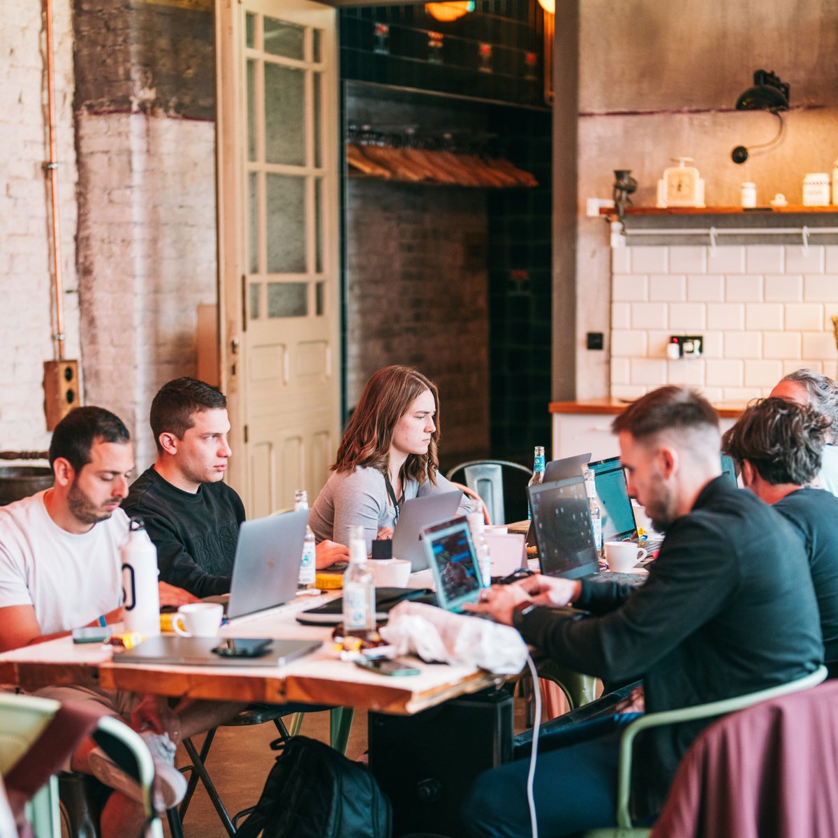 Group of people working on laptops around a table.