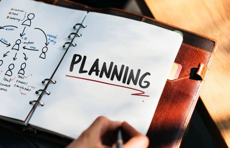 An open notebook with "PLANNING" written on one page and a business diagram on the other.