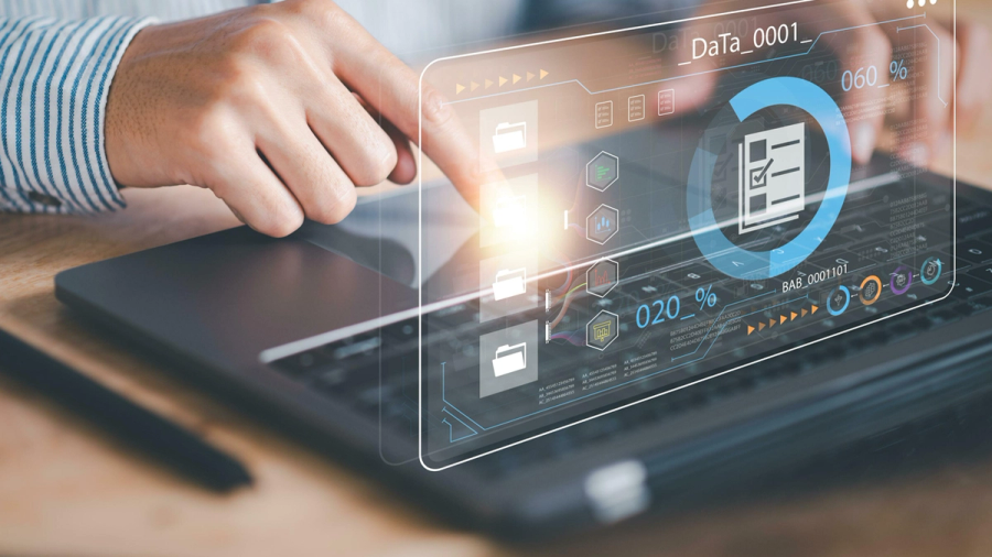 Hands interacting with a glowing futuristic digital interface showing data and file icons above a laptop.