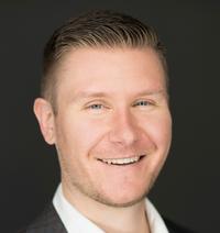 Smiling man with short brown hair and blue eyes.