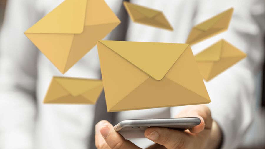 Email envelopes floating around a smartphone held by a person.