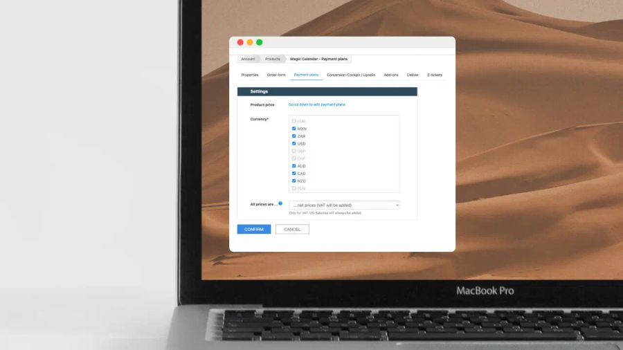 A MacBook Pro laptop displaying a payment settings interface with currency options over a desert landscape wallpaper.