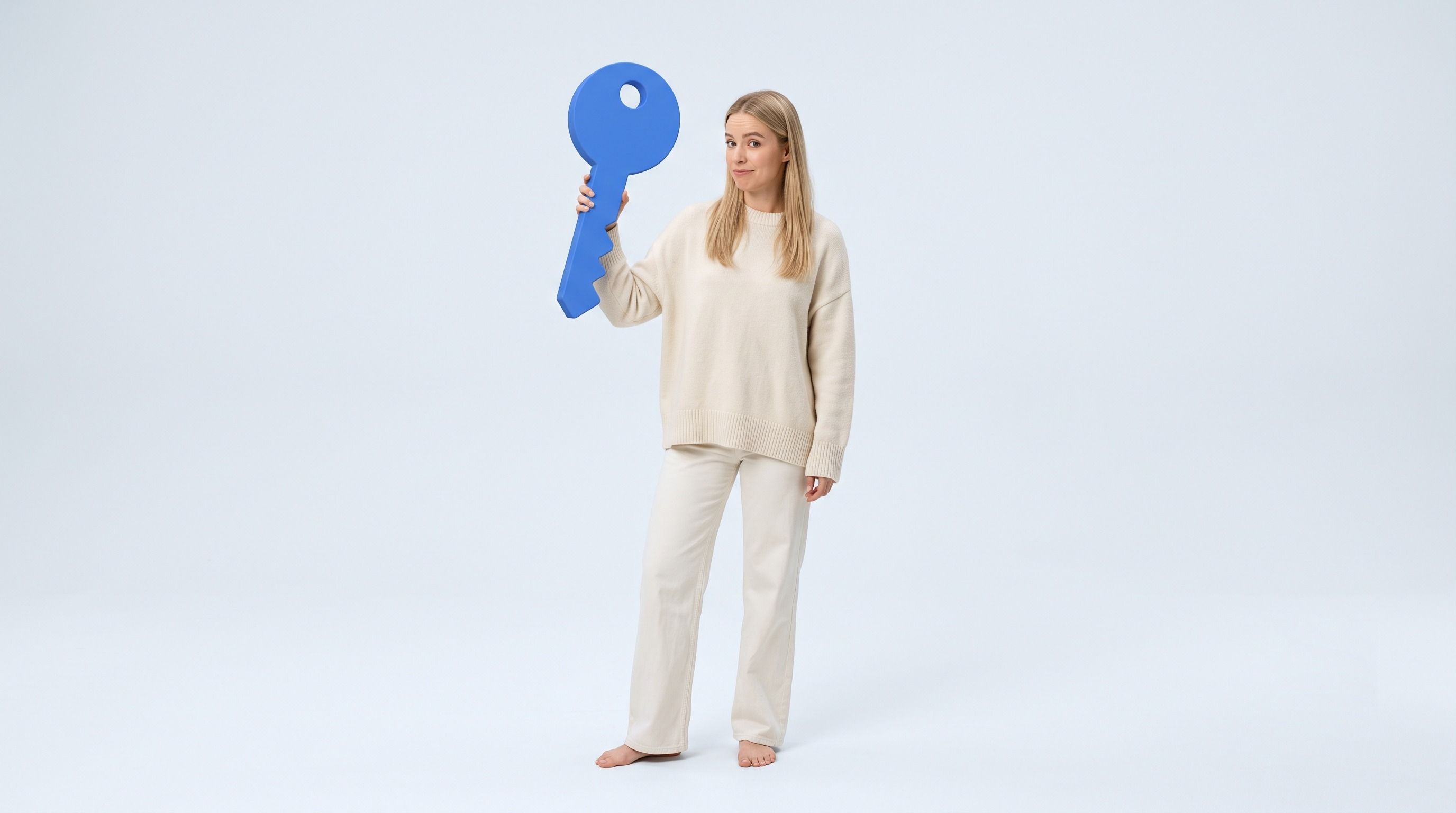 A woman in cream clothing holds up a large blue key.