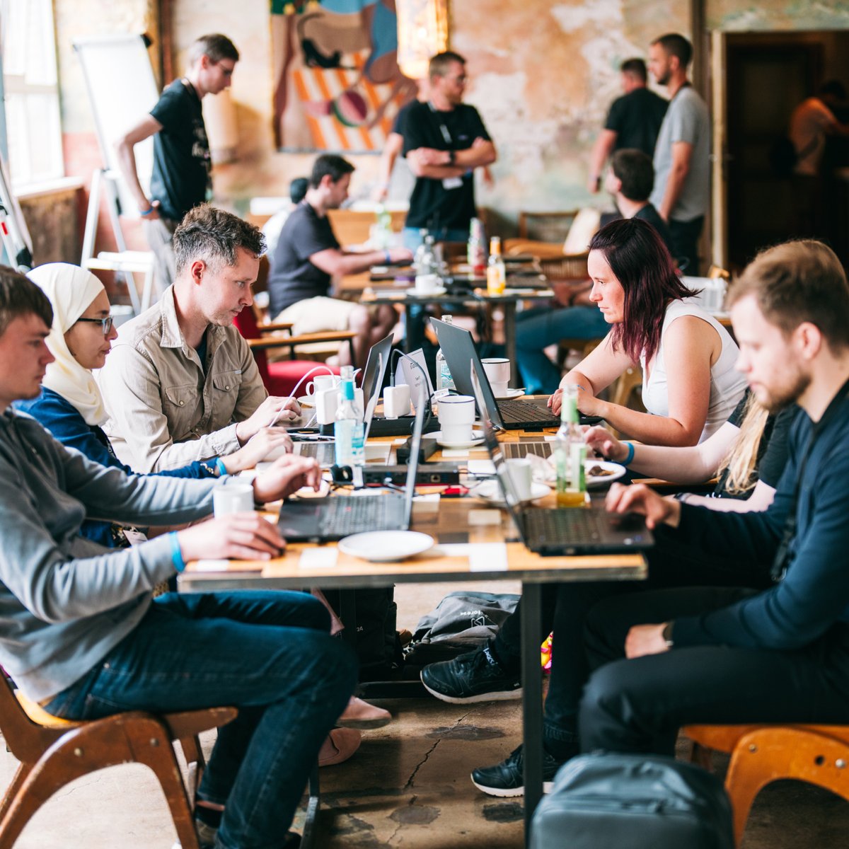 People working on laptops at tables in a casual co-working space.