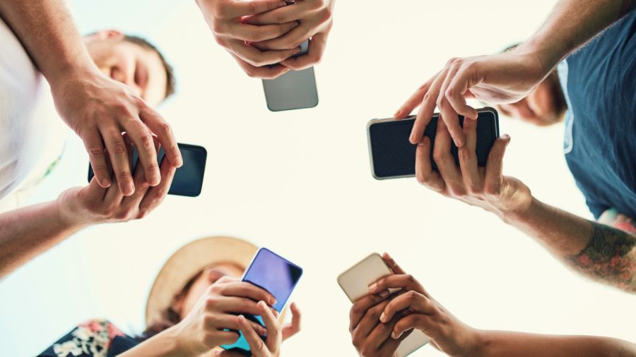 Low-angle shot of a circle of people looking down at their smartphones.