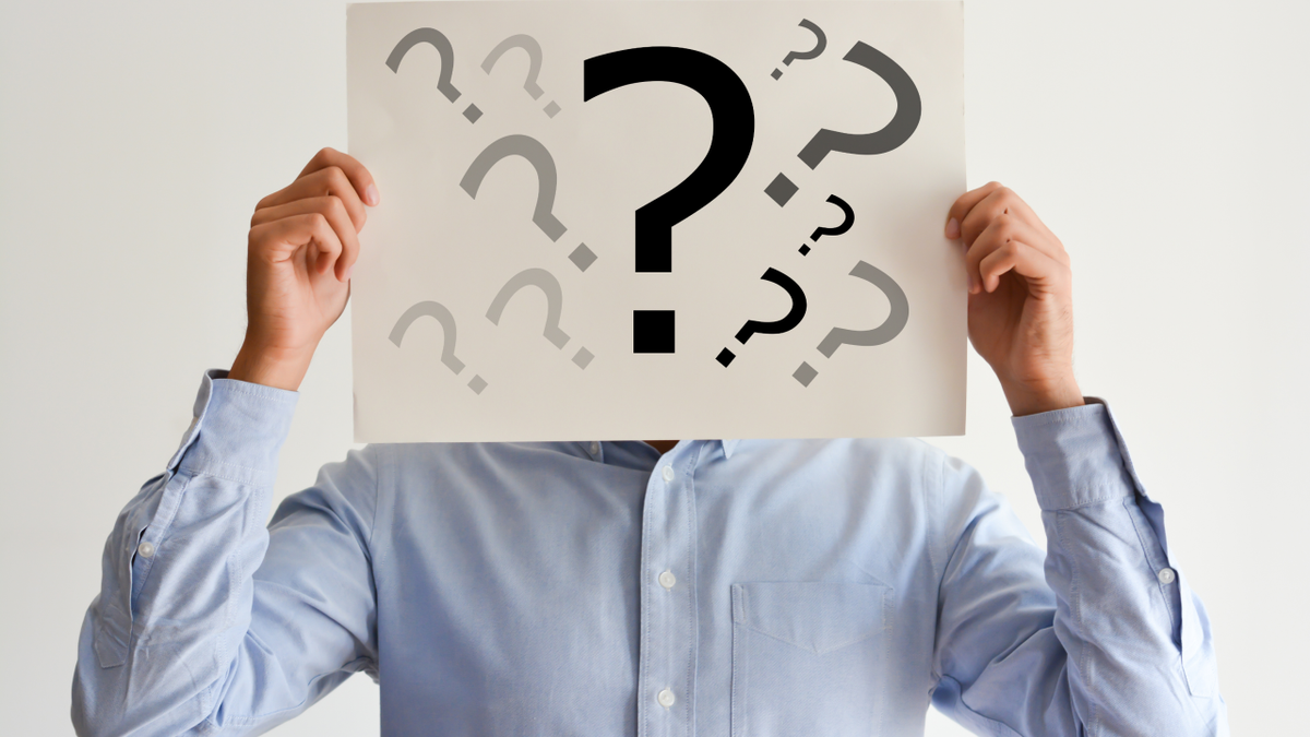 Person holding a paper with question marks over their face.