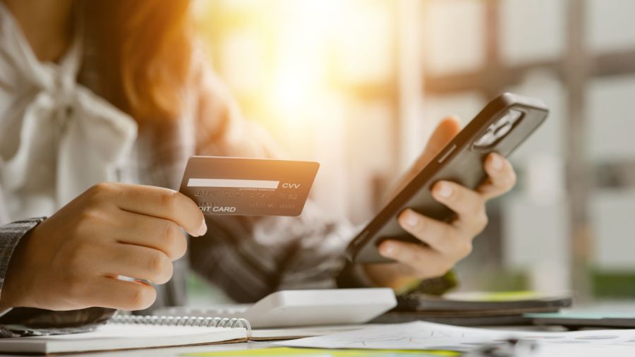 Hands holding a credit card and a smartphone.
