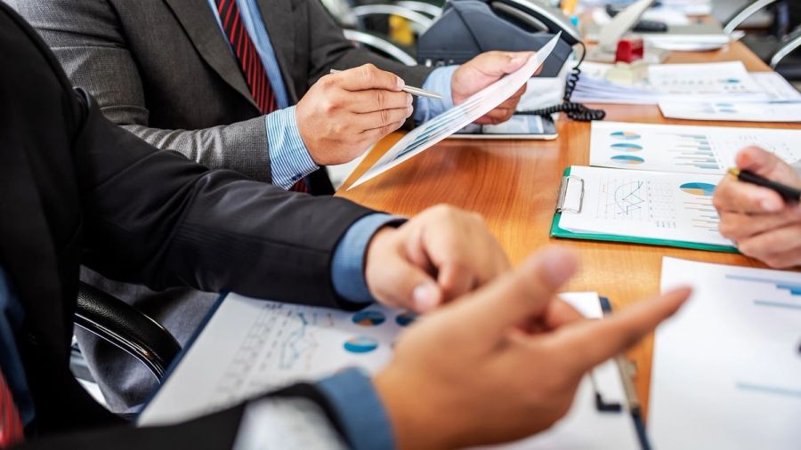Business professionals' hands reviewing charts and documents at a meeting.