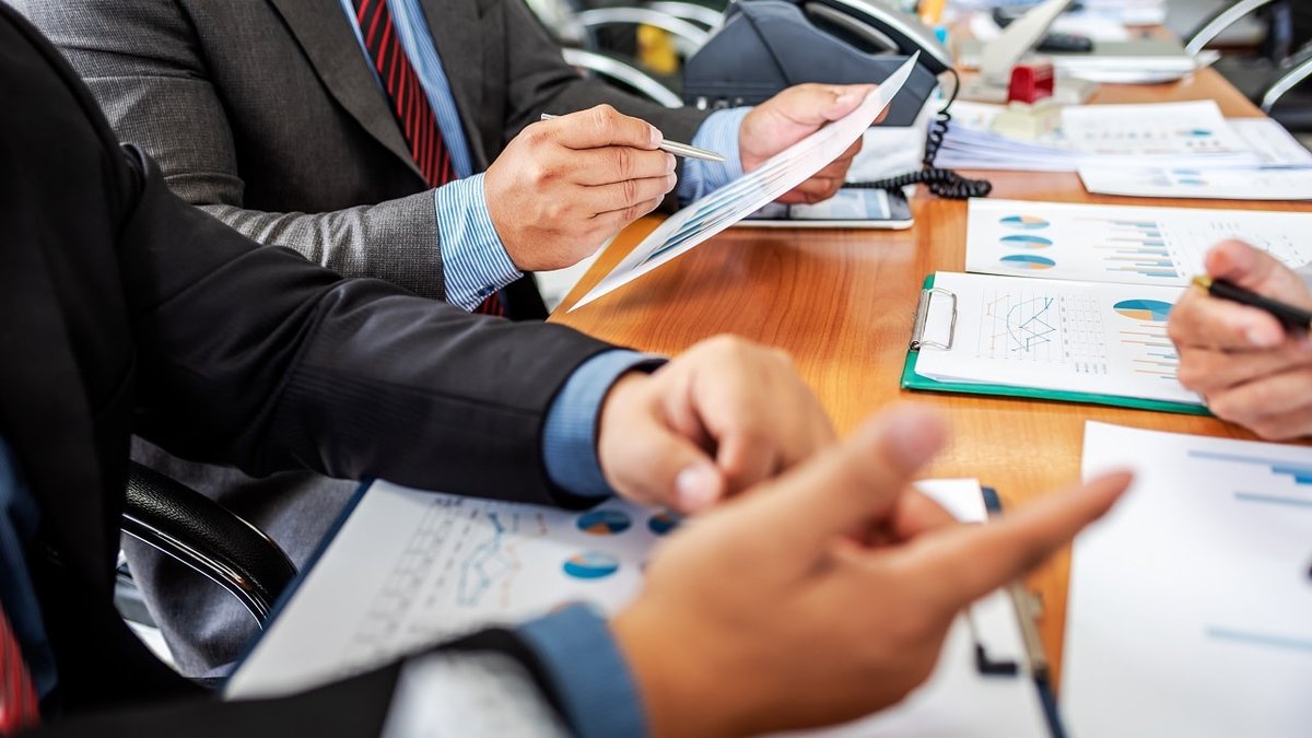 Business professionals' hands reviewing charts and documents at a meeting.