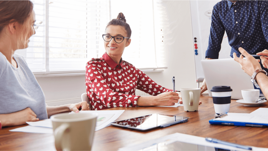 A group of diverse professionals collaborating at a meeting table in a bright office.