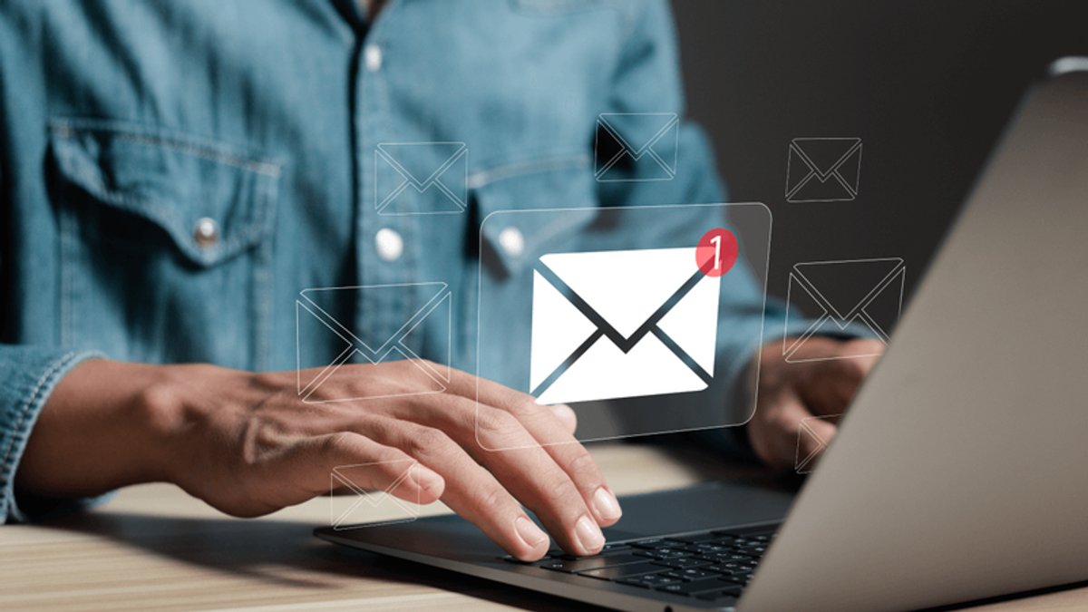 Hands typing on a laptop with a prominent email icon showing a new message notification.