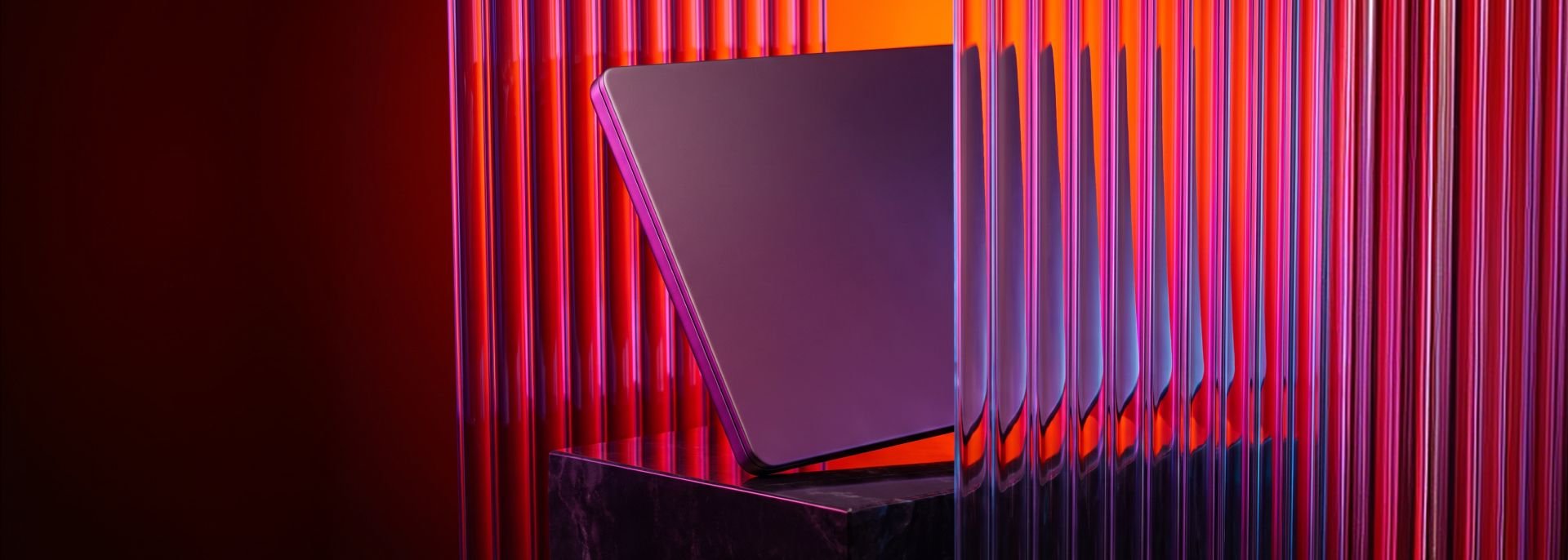 Dark rectangular device on a black pedestal, framed by vertical translucent rods with red and purple lighting.