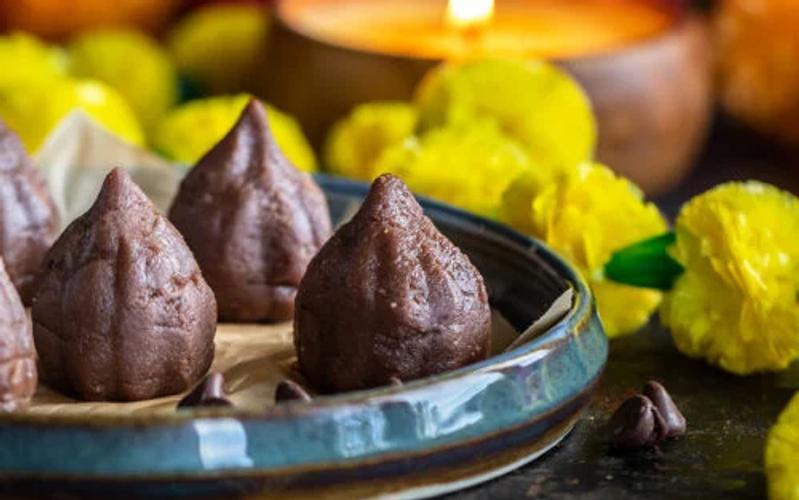 Chocolate mawa modak made with khoya and cocoa powder shaped by hand showing the traditional modak silhouette alongside pure chocolate shell modak on a festival plate