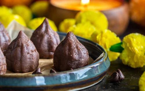 Chocolate mawa modak made with khoya and cocoa powder shaped by hand showing the traditional modak silhouette alongside pure chocolate shell modak on a festival plate