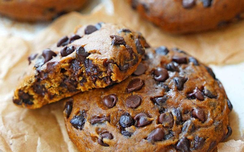 Close up of homemade pumpkin chocolate chip cookies with melted semi-sweet chocolate chips showing soft cakey texture on a parchment lined baking sheet