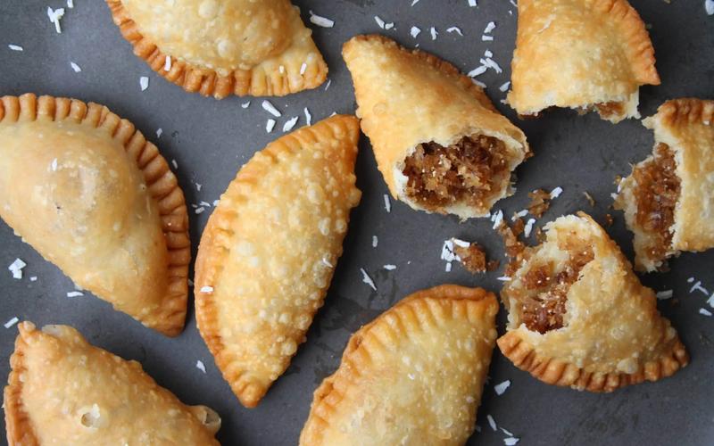 Step by step karanji recipe showing pastry circle being filled with coconut jaggery mixture sealed with water and crimped with fork before deep frying
