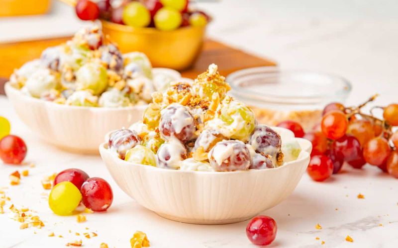 Copycat chicken salad chick grape salad showing creamy cream cheese dressing on mixed grapes with pecan pieces and brown sugar topping for a Southern potluck side dish