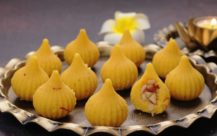 Step by step mawa modak recipe showing khoya cooking in a heavy pan and shaped modak garnished with saffron and pistachios for festival gifting