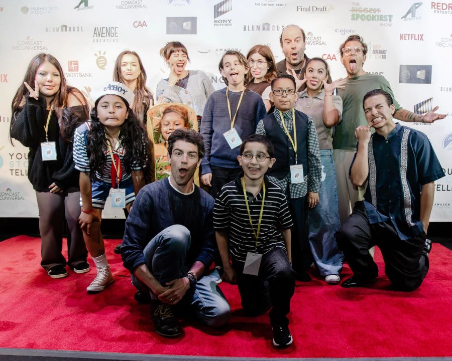 A group of actors and students making funny faces on a red carpet