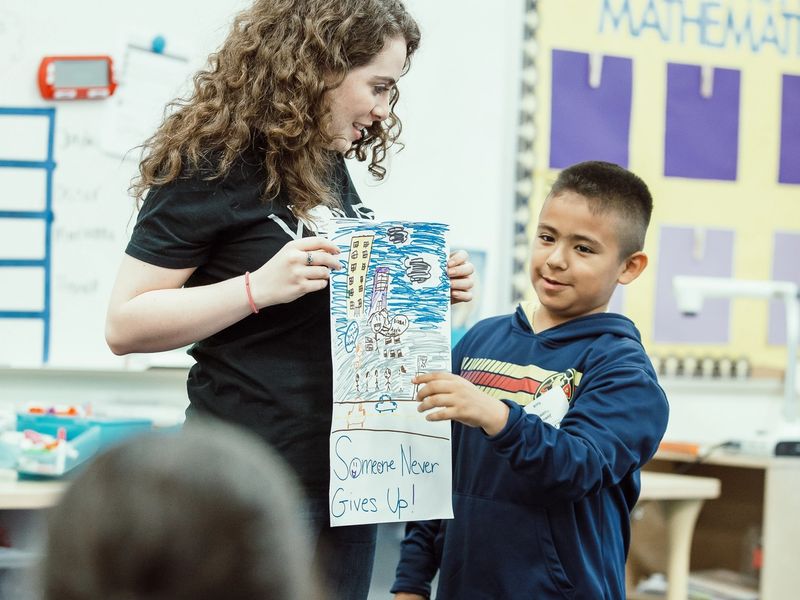 A student points to a poster held by a mentor