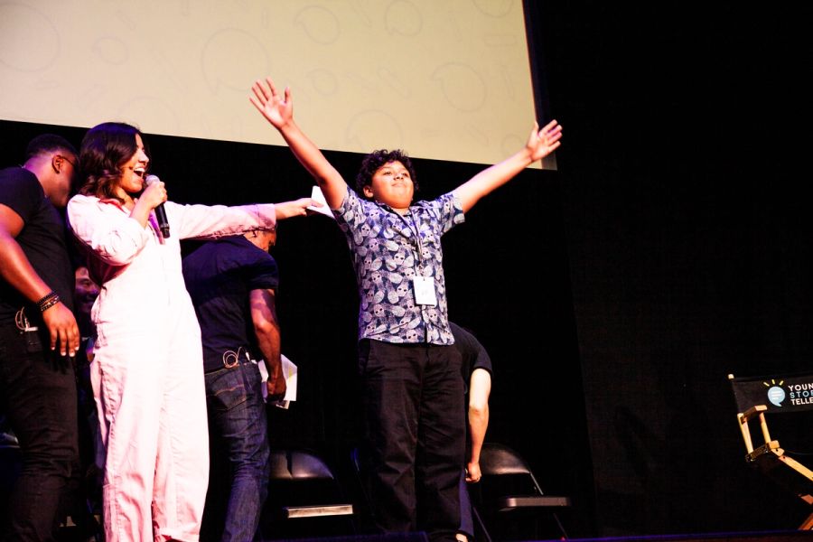 A woman gestures to a boy who holds his arms out triumphantly