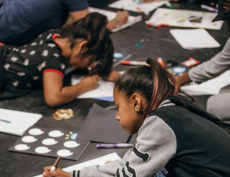 Students creating story posters while seated on the ground