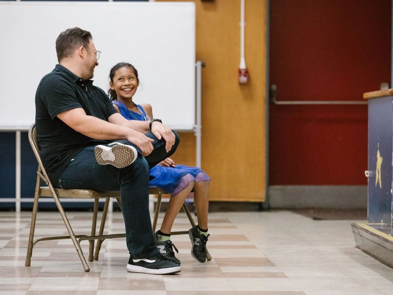 A girl sits next to a man, smiling
