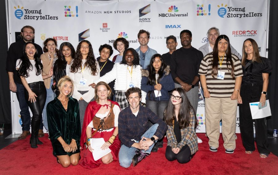 A group of actors and students smiling on a red carpet