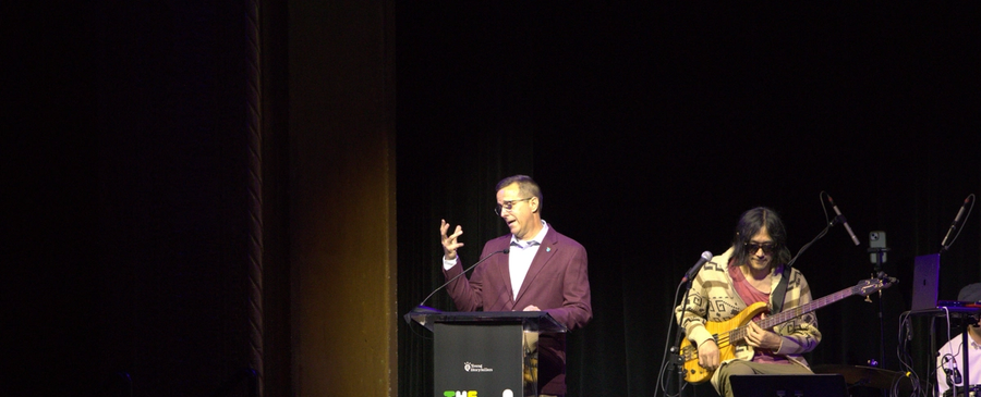 A man stands at a podium, speaking