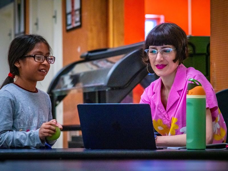 A student and mentor seated at a table in front of a laptop