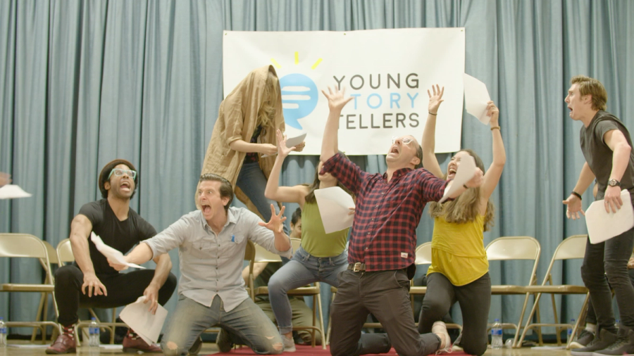 A group of actors on the stage frozen in silly poses, kneeling on the ground